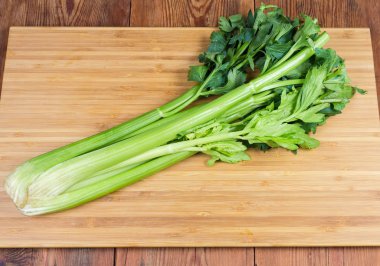 Fresh celery stalks on the cutting board on rustic table clipart