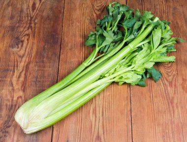 Fresh bunch of celery stalks on the rustic table clipart