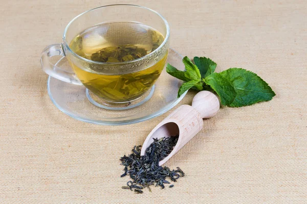 Szárított zöld tea levelek, menta, üveg csésze teát készített — Stock Fotó