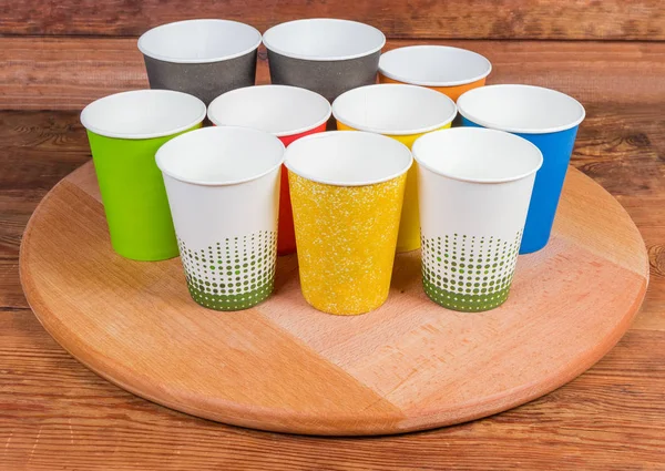 Different empty disposable paper cups on the wooden serving board