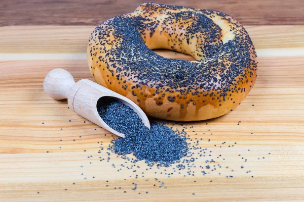 Poppy seeds in spice spoon, bagel sprinkled with poppy seeds — Stock Photo, Image