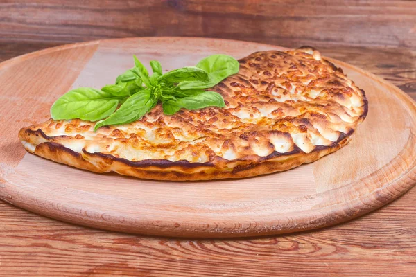 Gebackene Calzone mit Basilikumzweig auf Pizzaschachtel Nahaufnahme — Stockfoto