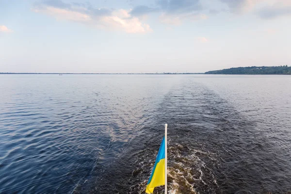 Schiffsspuren auf dem Wasser und ukrainische Nationalflagge im Vordergrund — Stockfoto