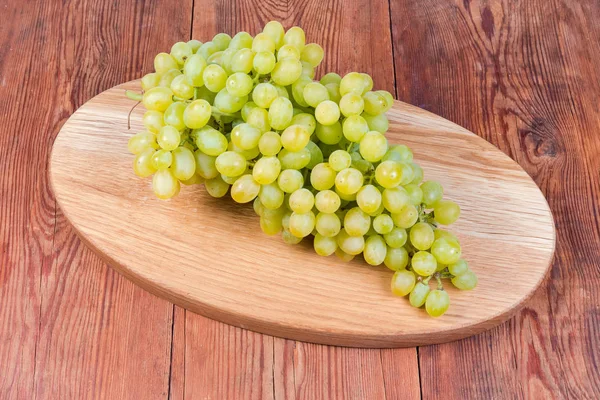 Racimo de uvas Sultana en el tablero de servir de madera ovalada — Foto de Stock