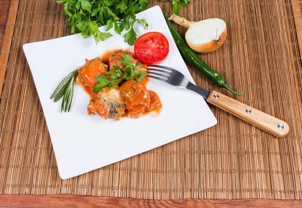 Konserwy rybne w sosie pomidorowym na naczyniu, zieleni i warzywach — Zdjęcie stockowe