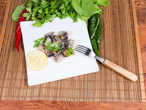 Poisson en conserve sur plat avec fourchette parmi les légumes et les légumes verts — Photo