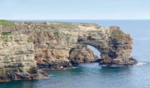 Rocky sea coast with natural limestone rocky arch