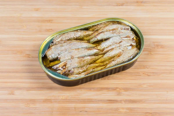 Canned sprats in open tin can on wooden surface — Stock Image Canned sprats in open tin can on wooden surface Stock Picture