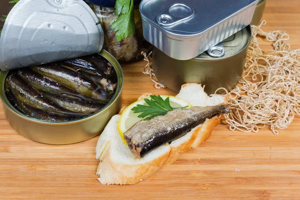 Sprats in open tin can, open sandwich against other cans — Stock Image Sprats in open tin can, open sandwich against other cans Royalty Free Stock Photos
