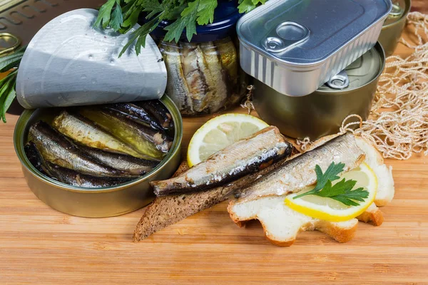Sprats in open tin can, open sandwiches against other cans — Stock Image Sprats in open tin can, open sandwiches against other cans Stock Image