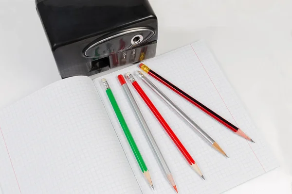 Electric pencil sharpener and pencils on exercise book, top view — Stock Photo, Image