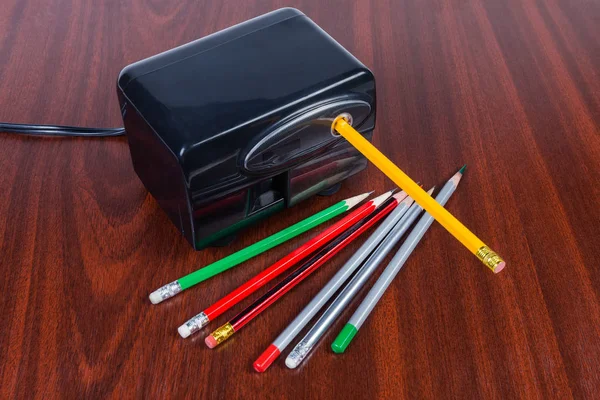 Desk electric pencil sharpener and pencils on the wooden table — Stock Photo, Image