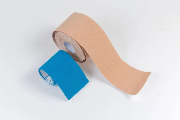 Blue anf flesh-colored elastic therapeutic tapes on light surface — Stock Photo, Image