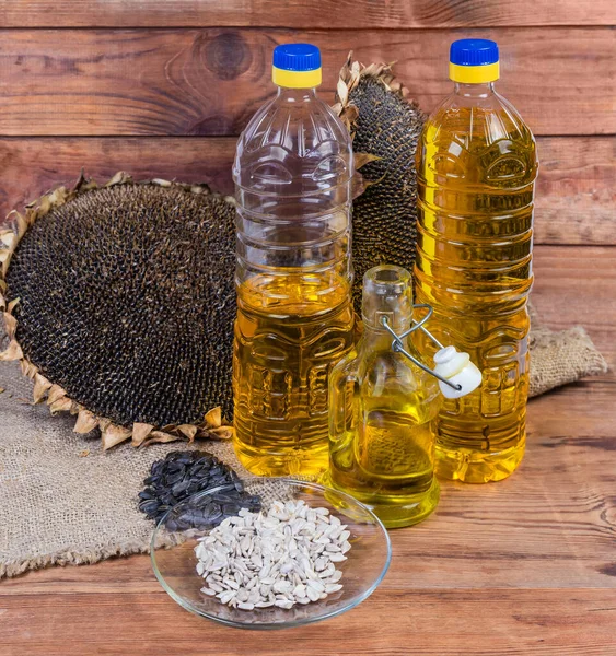 Huile de tournesol en différentes bouteilles parmi les graines et les têtes de tournesol — Photo