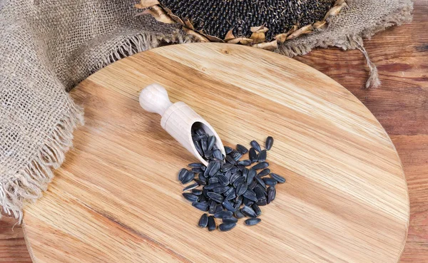 Sementes de girassol na superfície de madeira contra a cabeça de girassol seco — Fotografia de Stock