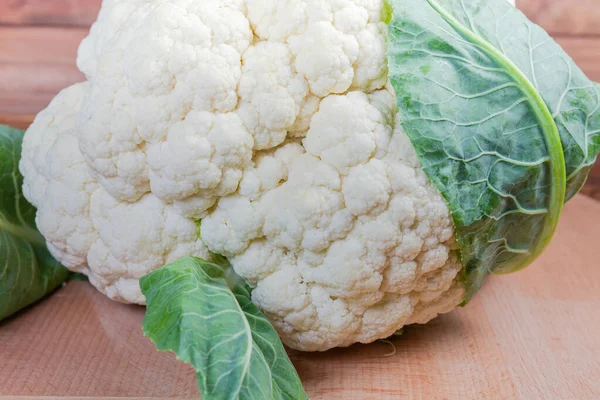 Fresh cauliflower head on the wooden surface, fragment close-up — Stock Photo, Image