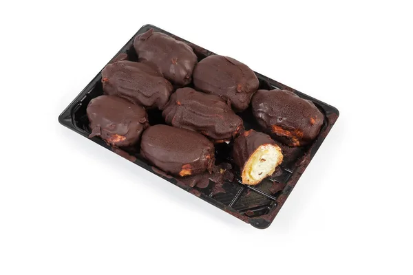 Eclairs mit Schokoladenglasur auf Plastikverpackung auf weißem Hintergrund — Stockfoto