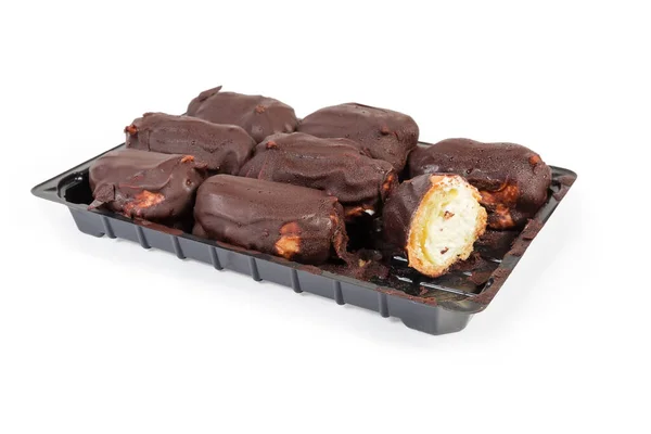 Eclairs mit Schokoladenglasur auf Plastikverpackung auf weißem Hintergrund — Stockfoto