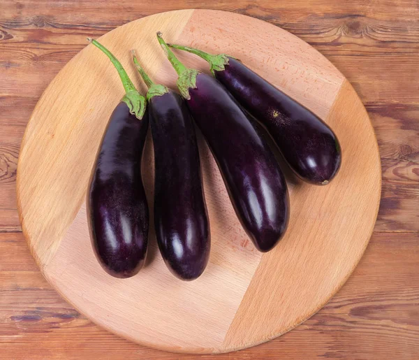 Bovenaanzicht van verse paarse aubergines op houten serveerbord — Stockfoto