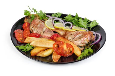 Okyanusun pişmiş leşleri, domatesli ve kızarmış patatesli soğan ve limon dilimleri ve siyah arka planda yeşil tabakla servis ediliyor.