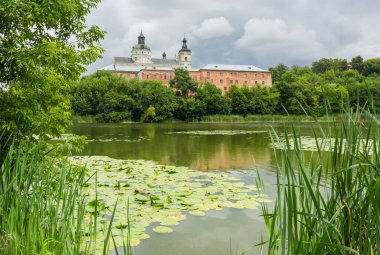 Former fortified Monastery of the Order of Discalced Carmelites of the 17th century. General view of the monastery over water in cloudy weather, Berdychiv, Ukraine clipart
