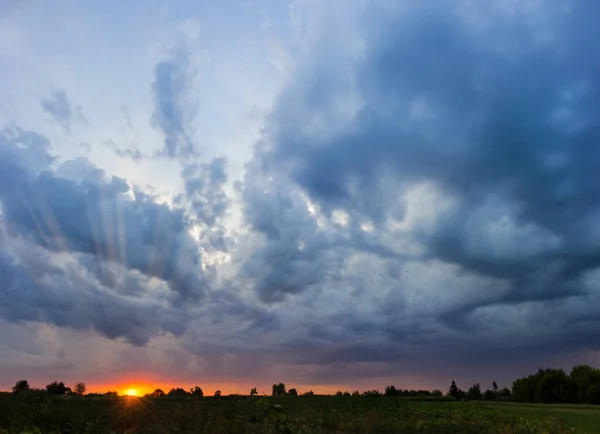積雲と嵐の雲の空と日没時に畑の上に太陽を沈む — ストック写真