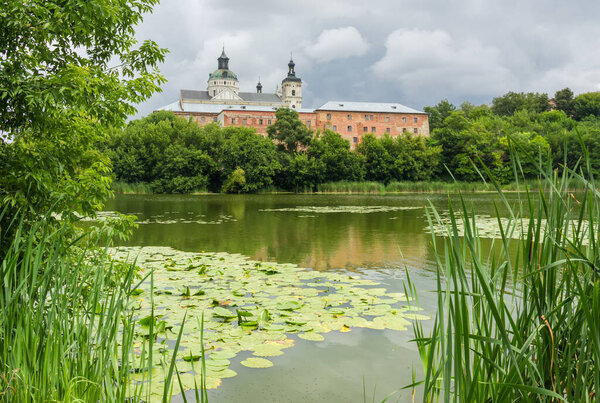 Former fortified Monastery of the Order of Discalced Carmelites of the 17th century. General view of the monastery over water in cloudy weather, Berdychiv, Ukraine