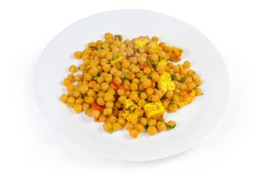 Haşlanmış nohut, domatesle pişirilmiş, Adighe peyniri ve beyaz arka plandaki beyaz tabakta yeşiller.