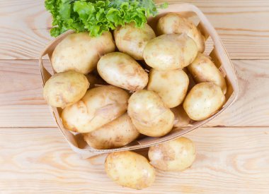 Çiğ, küçük ahşap sepetin içinde soyulmamış ince derili sarı patatesleri yıkadı.