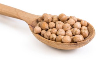 Beyaz arka planda, ahşap kaşıkta pişirilmemiş sarı nohut parçaları seçici bir odak noktasında.