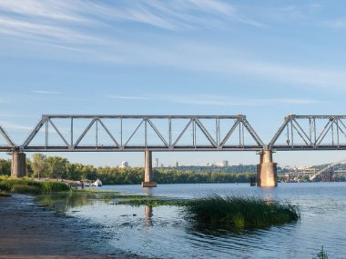 Demiryolu köprüsünün sol yakasında nehir boyunca çelik kirişler ve taş destekler var. Podilskyi Demiryolu Köprüsü Dinyeper Nehri üzerinde, Kyiv, Ukrayna