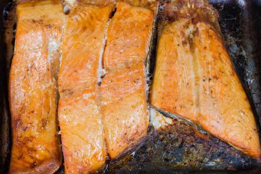 Kırsal metal fırın tepsisinde alabalık filetosunun fırınlanmış parçaları, en üstteki yakın plan, arka plan.