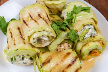 Izgara uzun kabak dilimleri. Beyaz tabakta çeşitli dolgular var. Yakın plan.