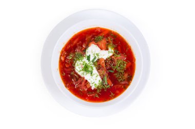 Tipik kırmızı pancar çorbası, ekşi kremayla tatlandırılmış ve beyaz arka planda servis edilen taze kesilmiş otlarla serpilmiş.