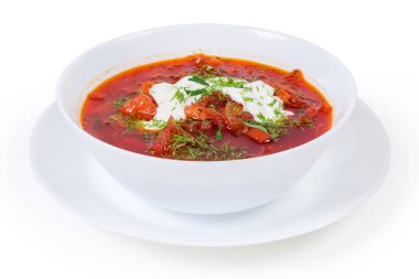 Tipik kırmızı pancar çorbası. Ekşi kremayla tatlandırılmış. Kasede servis edilen taze doğranmış otlar beyaz arka planda.