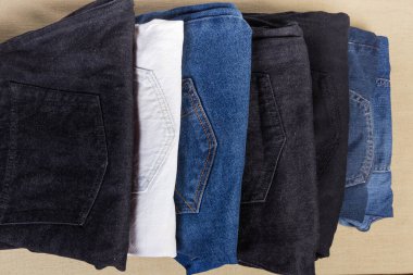 Farklı kot pantolonlar, farklı renkler ve desenler, katlanmış arka cepler, parçalı üst görünüm yakın plan,