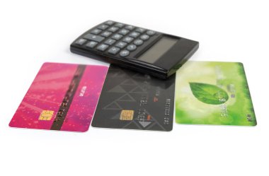 Elektronik cep hesap makinesinin bulanık arka planındaki farklı plastik banka kartları beyaz arkaplanda, seçici odak noktasında yakın plan