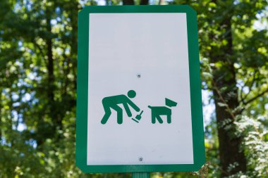Köpek sahipleri için parkta reçeteli tabela. Evcil hayvanlarının dışkılarını toplama ihtiyacı hakkında. Yakın plan.