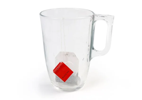 Egy Zacskó Fekete Tea Piros Címkével Üres Üvegpohárban Fehér Alapon — Stock Fotó