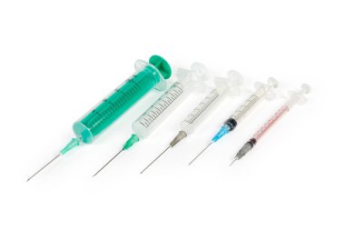 Tek kullanımlık plastik şırıngalar farklı boyutlarda, beyaz arka planda deri içi ve kas içi iğneler var.