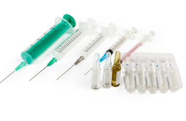 Tek kullanımlık plastik şırıngalara karşı farklı boyutlarda ve beyaz arka planda iğneli ilaçlar.