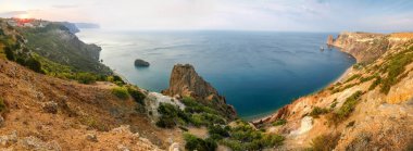 Güneş doğarken sarp kıyıları ve kıyı uçurumları olan deniz koyunda, yukarıdan geniş panoramik manzara