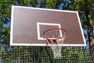 Açık hava spor sahasına sepet monte edilmiş basketbol sehpası, park dallarının arka planında manzara
