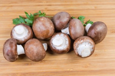 Tahta kesme tahtasının üzerinde taze taze taze kraliyet şampiyonları ve maydanoz dalları yığını.