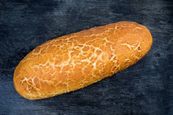 暗い表面に網状の地殻を持つ小麦パンの全楕円形のパン トップビュー — ストック写真