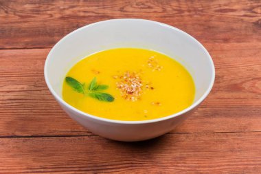 Kabak çorbası püresi, kırmızı mercimek, susamlı ve yeşil dallarla süslenmiş eski kırsal masada, yakın plan.