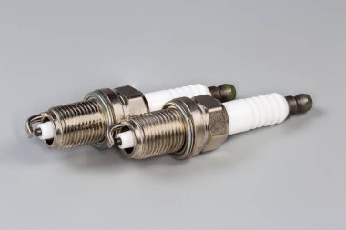 Gri bir arka planda, içten yanmalı motorun ateşleme sistemi için bir tarafı elektrot olan iki yeni buji.