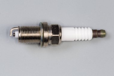 Gri arkaplandaki içten yanmalı motorun ateşleme sistemi için bir tarafı elektrot olan yeni buji.