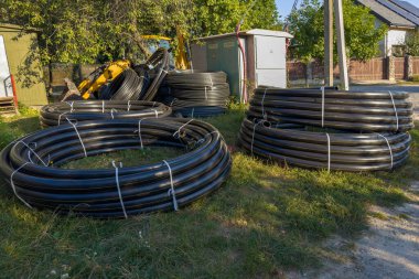 Şehir doğalgaz boru hattı inşaatı için sarı işaretli farklı çaplı siyah yuvarlak plastik borular güneşli bir akşamda açık havada uzanır.