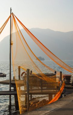 Fishing nets attached to a pole with panorama of the Iseo lake clipart
